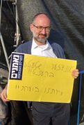 חרדי נושא שלט ביידיש: "אונדזער שטעטל ברענט!". ירושלים, 13 בפברואר 2023