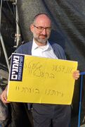 חרדי נושא שלט ביידיש: "אונדזער שטעטל ברענט!". ירושלים, 13 בפברואר 2023